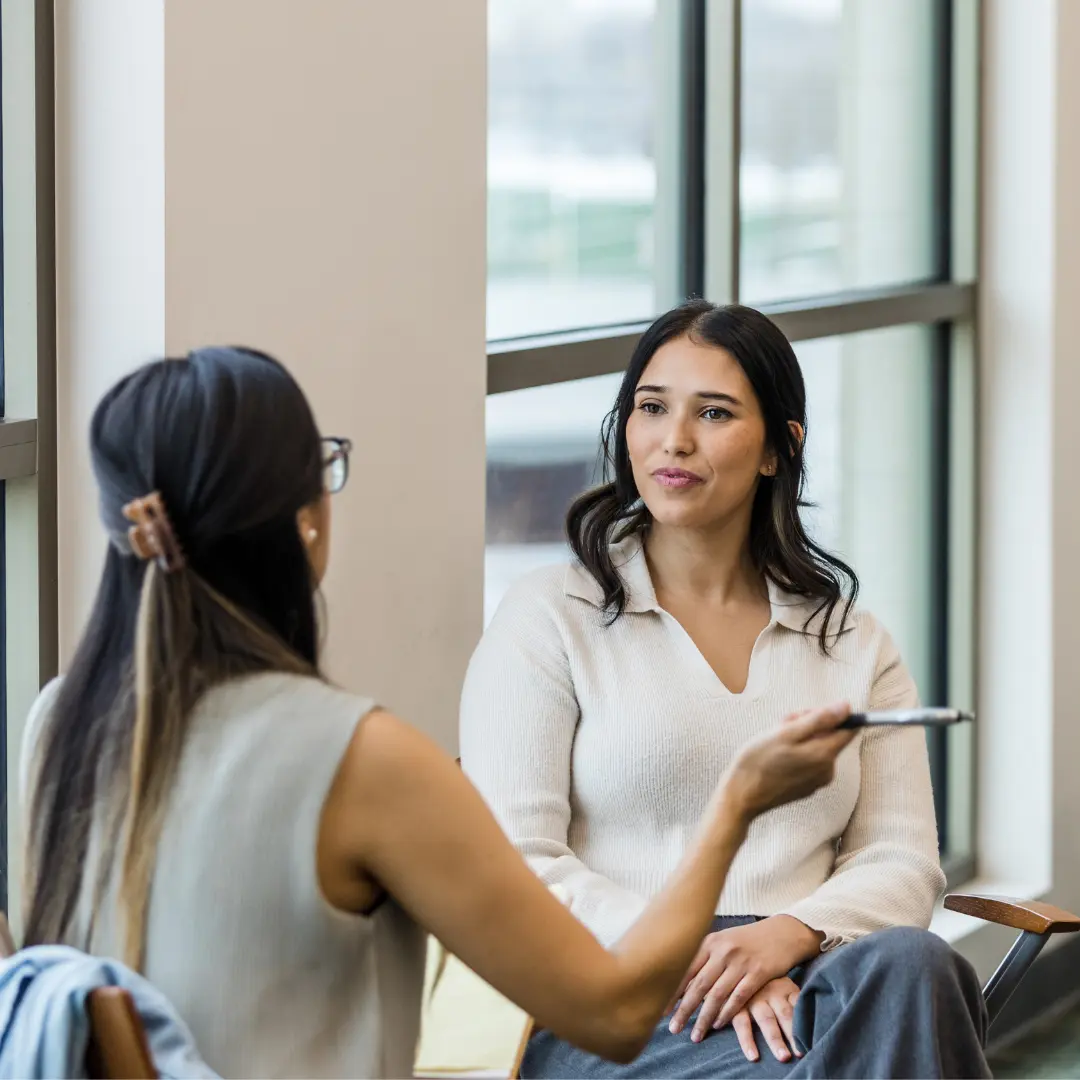 two women sitting down and talking to each other