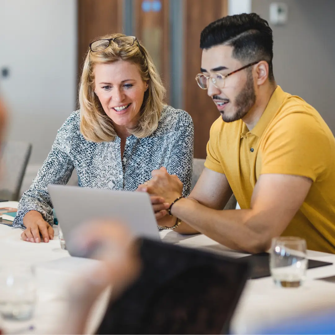 two people sitting together looking at a laptop